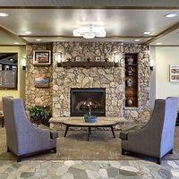 Hotel lobby with a welcoming stone fireplace surrounded by armchairs and decorated with framed pictures