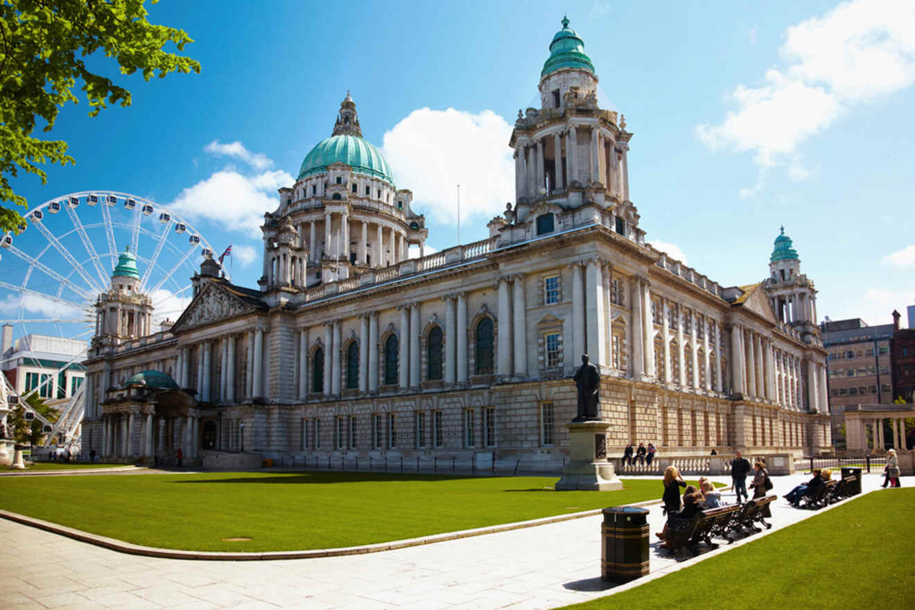 Majestic Belfast City Hall with its Baroque Revival architecture, green copper domes, and grand facade, featuring a statue in front and a Ferris wheel in the background under a clear blue sky