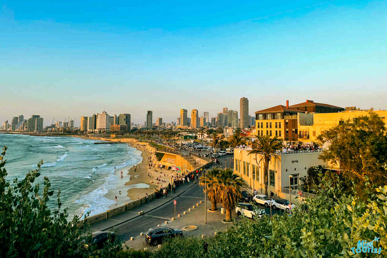 The golden hour casts a warm glow on Jaffa's scenic coastline, showcasing the bustling beach, promenade, and a backdrop of modern city skyscrapers contrasting with the historic architecture in the foreground