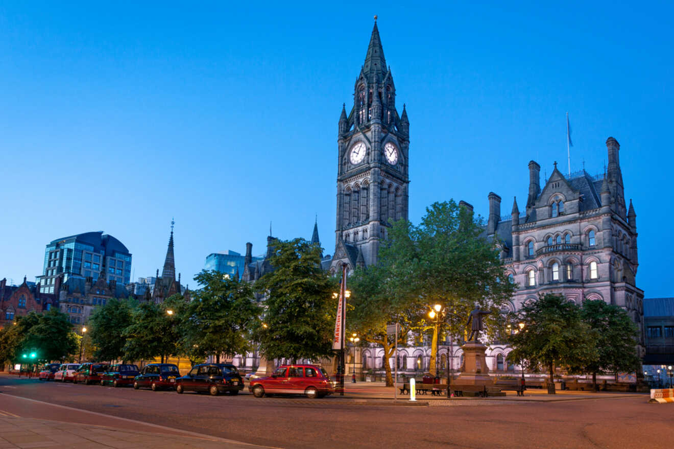 The iconic Manchester Town Hall stands majestically in the evening light, surrounded by modern buildings, with the street in the foreground lined with traditional black cabs awaiting passengers