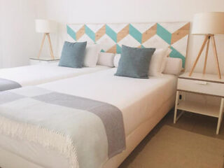 Chic twin bedroom with a geometric headboard in turquoise and white, crisp bedding, and matching bedside lamps