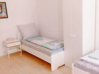 Bright and minimalistic private bedroom with a single bed, white bedding, a small nightstand, and light wooden flooring