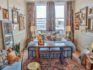Cozy, well-decorated bedroom area with eclectic furnishings and a large window providing ample natural light.