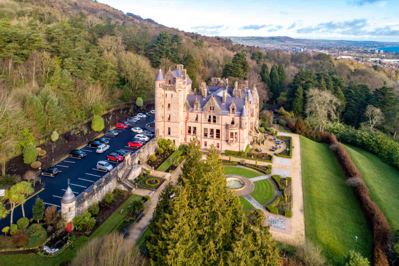 Aerial view of the grand Belfast Castle Estate with manicured gardens, against the lush backdrop of Cave Hill, on a clear day showcasing Belfast's natural and architectural beauty