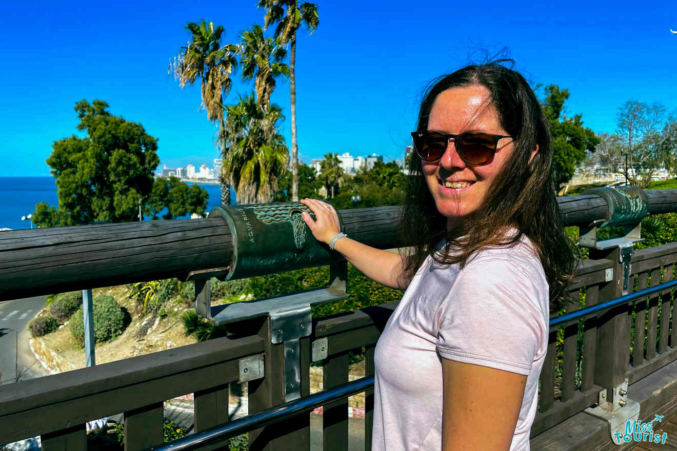 The author of the post smiling as she touches an ancient cannon overlooking the serene Mediterranean Sea from a vantage point in Jaffa