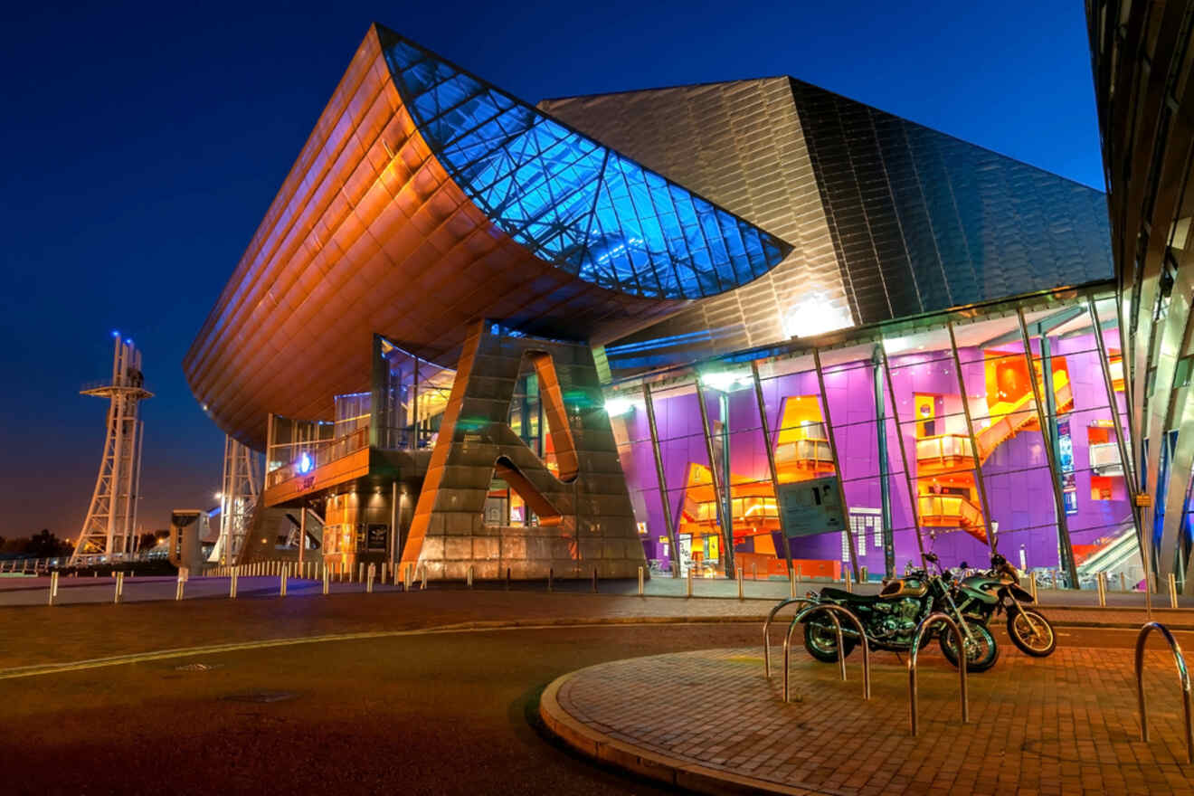 Exterior night view of The Lowry theater in Manchester, highlighted by its modern architecture with colorful lighting and a nearby waterfront