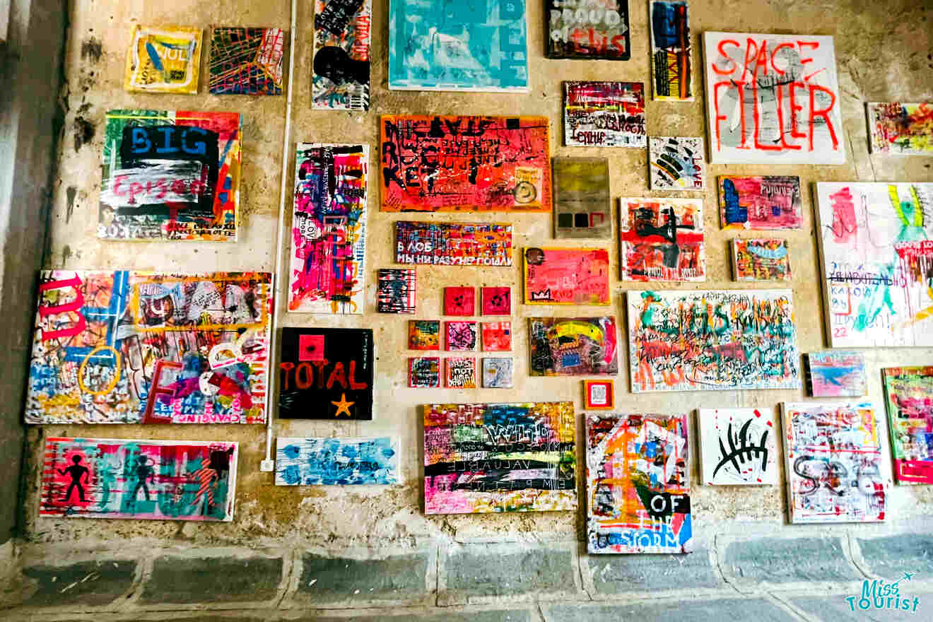 A colorful collage of mixed-media art pieces displayed on an ancient stone wall