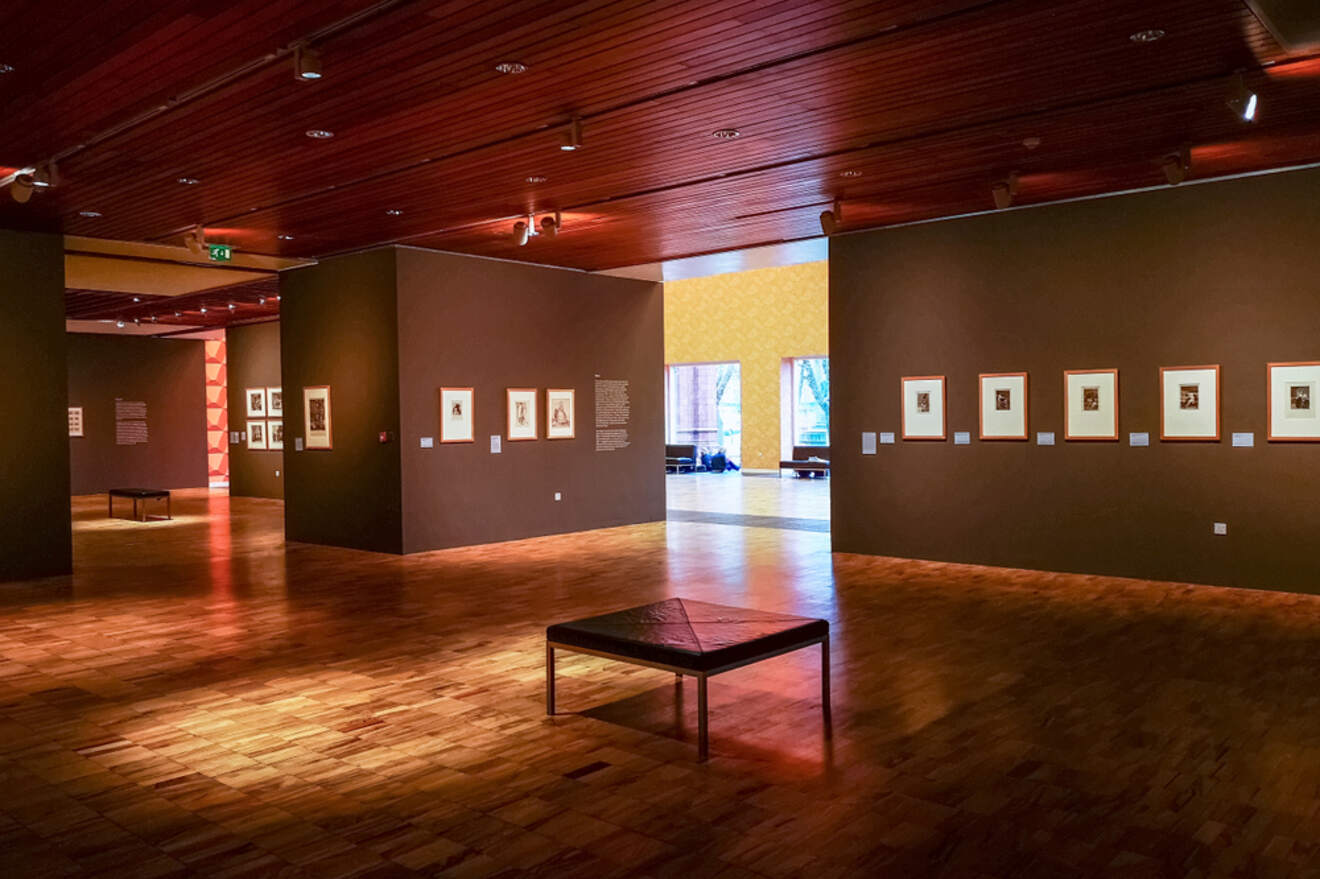 Interior of the Whitworth Art Gallery in Manchester, showcasing an art exhibition with framed works on dark walls and a polished wooden floor