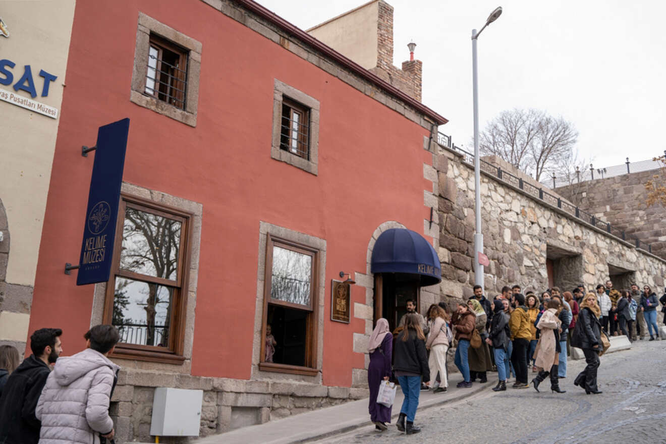 A crowd of visitors queued outside the Kelime Museum in Ankara, with the building's vibrant red façade inviting curiosity about the cultural artifacts housed within.