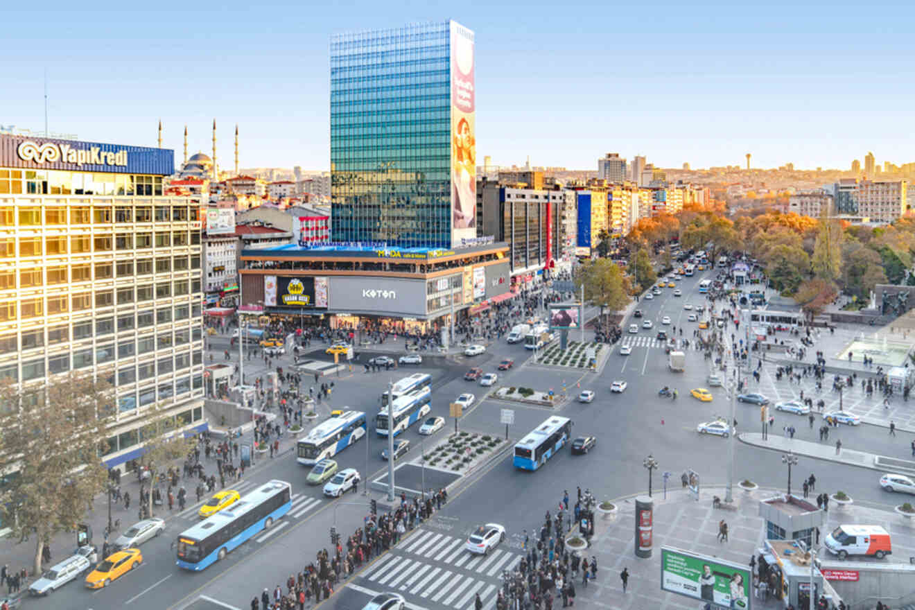 A bustling city intersection in Ankara during twilight, overlooking a lively crowd, city traffic, modern buildings, and the vivid colors of dusk setting in.