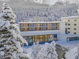 Snow-covered hotel facade with large windows, nestled in a winter landscape