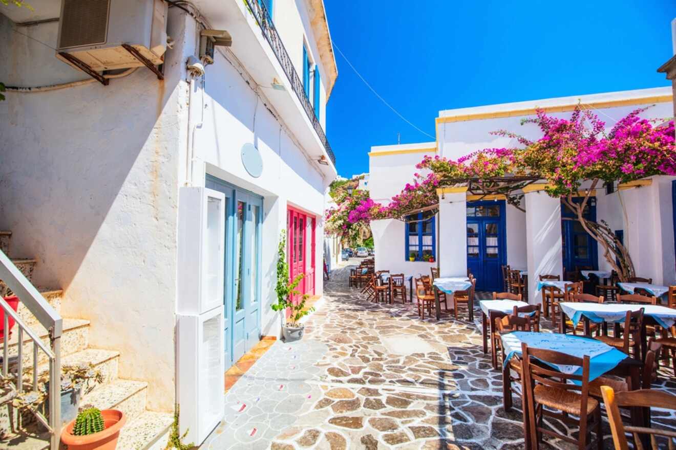 Vibrant alleyway in the Greek village Plaka with white walls and colorful doors, adorned with pink bougainvillea