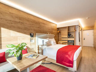 Modern hotel room with a bright red accent bed and a cozy living area
