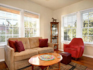 Bright, inviting living room with beige sofa, red accent chairs, and a round coffee table on a hardwood floor.