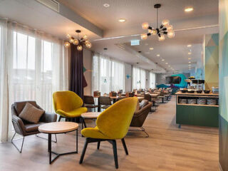 Spacious and contemporary hotel dining area with a variety of seating options, including stylish yellow chairs, under warm, decorative lighting