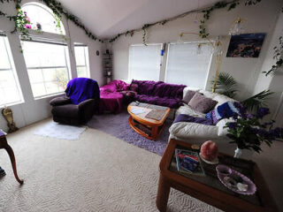 Eclectic living room with a purple sectional sofa, various plants, and personal touches