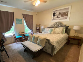 Homey guest bedroom with a sea-inspired decor, king-sized bed with patterned bedding, writing desk, and a cozy sitting area