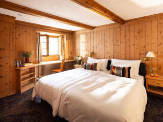 Rustic bedroom with natural wood walls and white linens