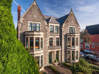 Stately stone-built Lincoln House with large windows, nestled in a residential area with lush greenery