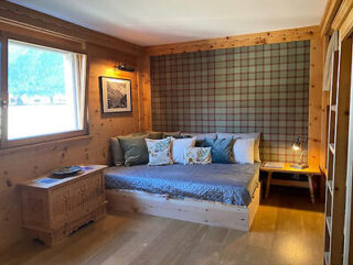 Alpine-style nook with plaid-covered bed and wooden interiors