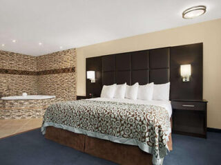 Luxurious hotel room with a patterned bedspread on a large bed, facing a tiled wall with a built-in spa bath