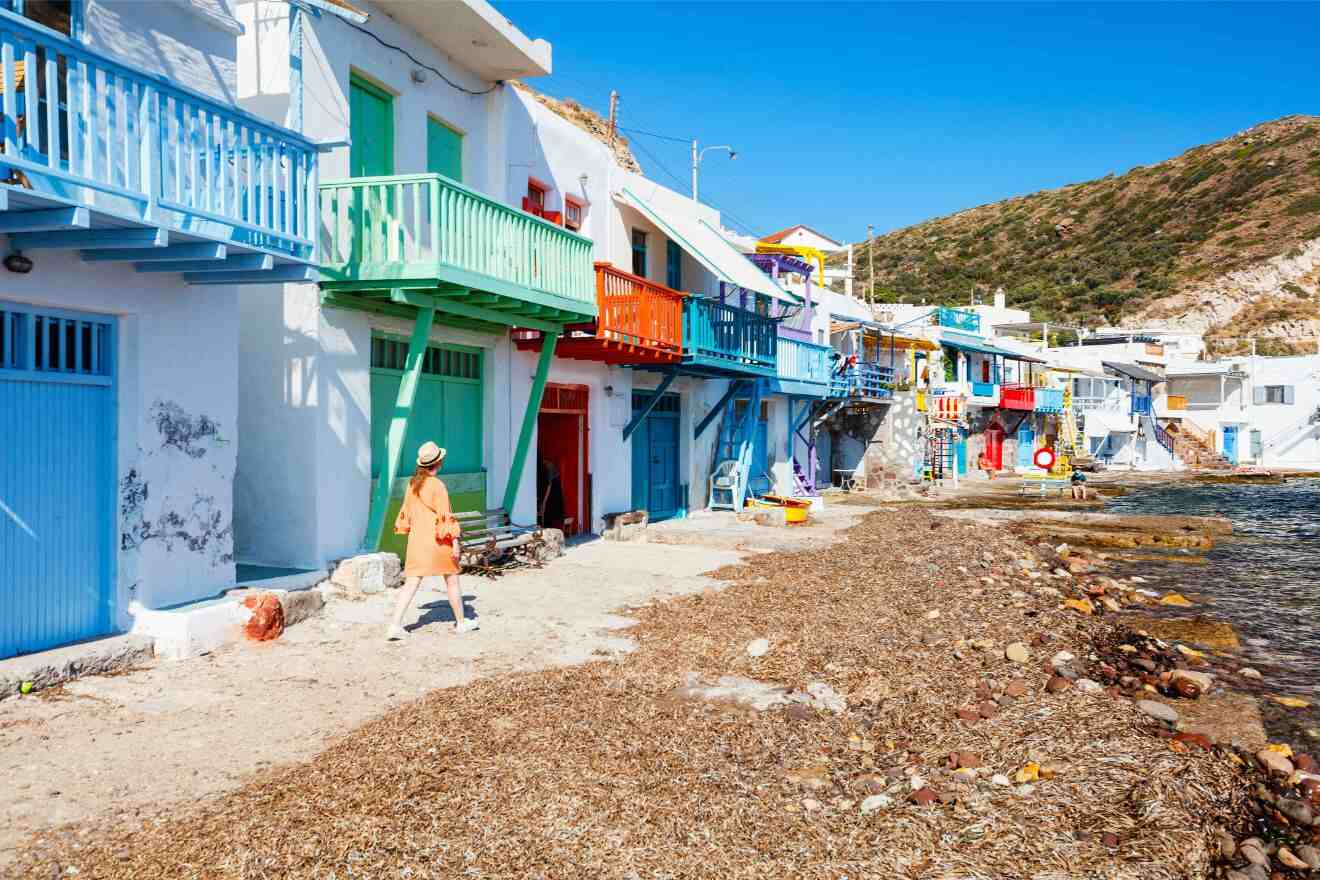 The charming coastal village Klima in Greece with colorful balconies and a woman in an orange dress walking by.