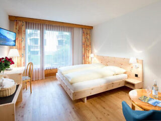 Bright hotel room with wood accents, cozy bedding, and a touch of blue.
