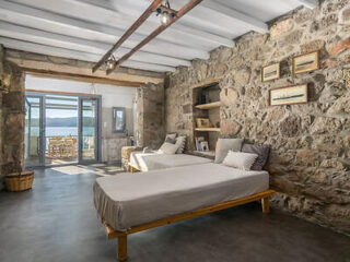 An eclectic bedroom with exposed stone walls, a plush daybed, and framed pictures