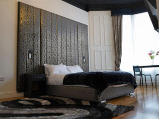 Elegant bedroom with a patterned feature wall and black bedding.
