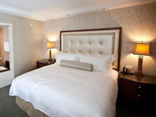 Town & Country Inn bedroom with a luxurious white tufted bed, patterned wallpaper, bedside lamps, and tasteful decor