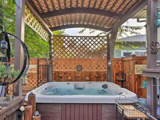 Private outdoor hot tub in a wood-paneled nook with hanging decorations and a privacy trellis.