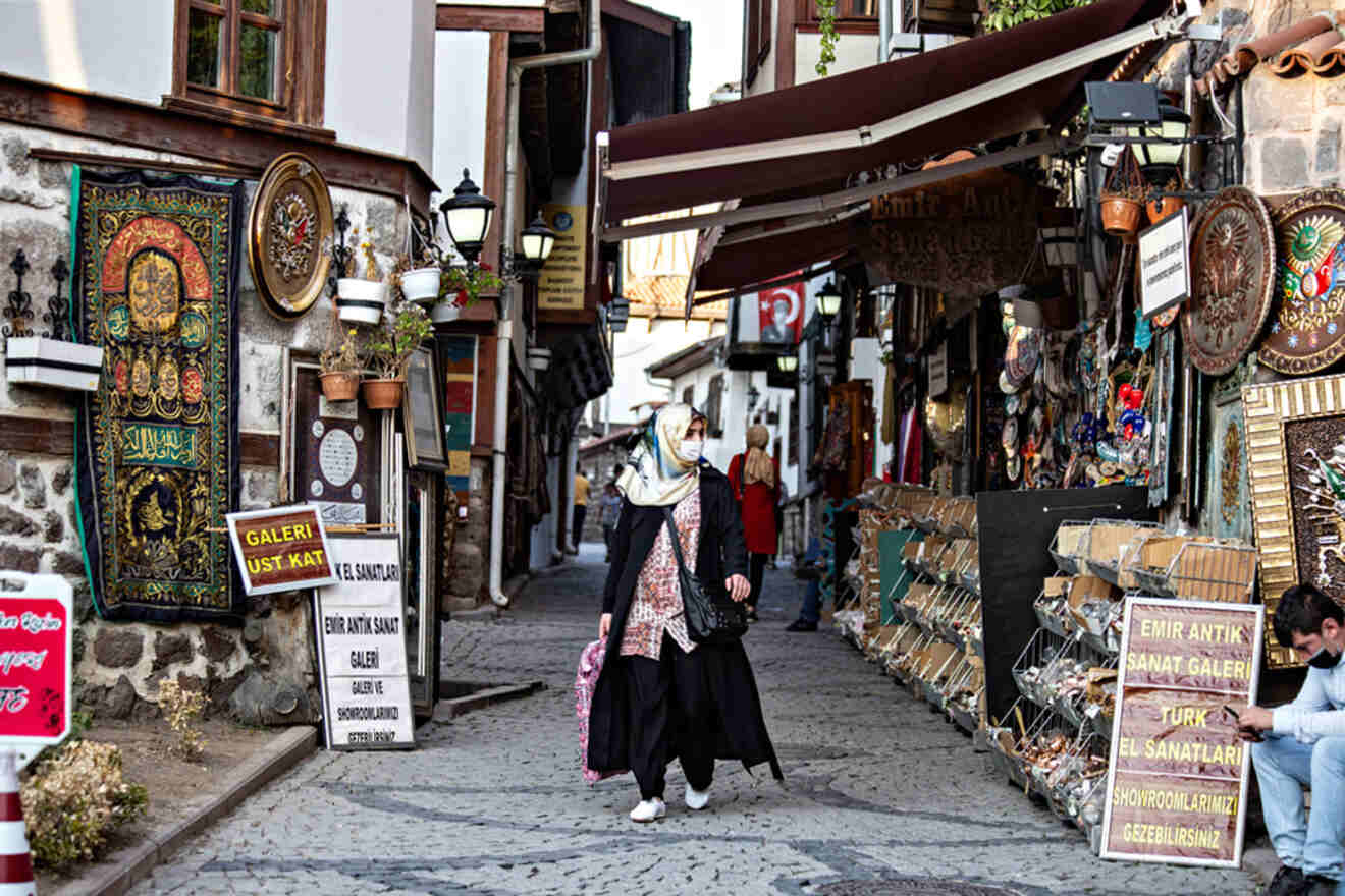 A lively street in Ankara's Old Quarter, lined with shops selling antiques and Turkish crafts, and people walking along the cobblestone pavement
