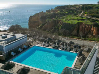 Rooftop pool with panoramic views of the sea and cliffs, loungers lined up for relaxation