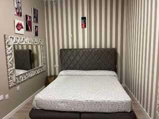 Bedroom with diamond-patterned headboard and striped wallpaper.
