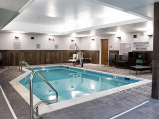 Indoor heated pool at Fairfield Inn & Suites with a well-lit pool area featuring grey tiles and clear blue water