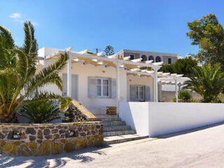 A bright white villa with palm trees in Greece, inviting with its open terraces and traditional design