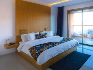 Spacious hotel room with a large comfortable bed, contemporary decor, and a sliding door leading