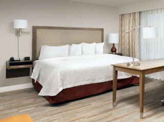 Contemporary hotel room with a king-sized bed, crisp white linens, and a minimalist work area