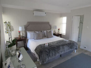 Elegant guest room at B&B on Buckingham featuring a plush bed with neutral linens, grey headboard, and fresh flowers