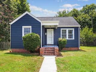 Charming exterior of Cozy Stay Cottage with a blue facade, white trim, and a welcoming entrance