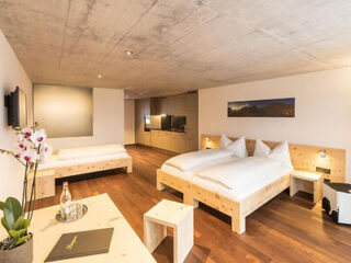 Spacious room with wooden furniture and white bedding, offering a contemporary Alpine feel