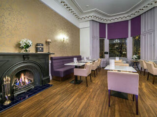 Dining room with a fireplace and purple-toned seating.