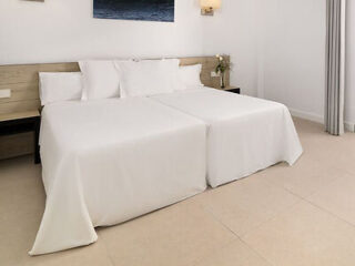 Sleek, contemporary bedroom in Hotel Médano with pristine white bedding, matching headboard and nightstands