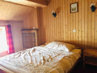 Traditional Engadine-style bedroom with natural wood paneling and red curtains