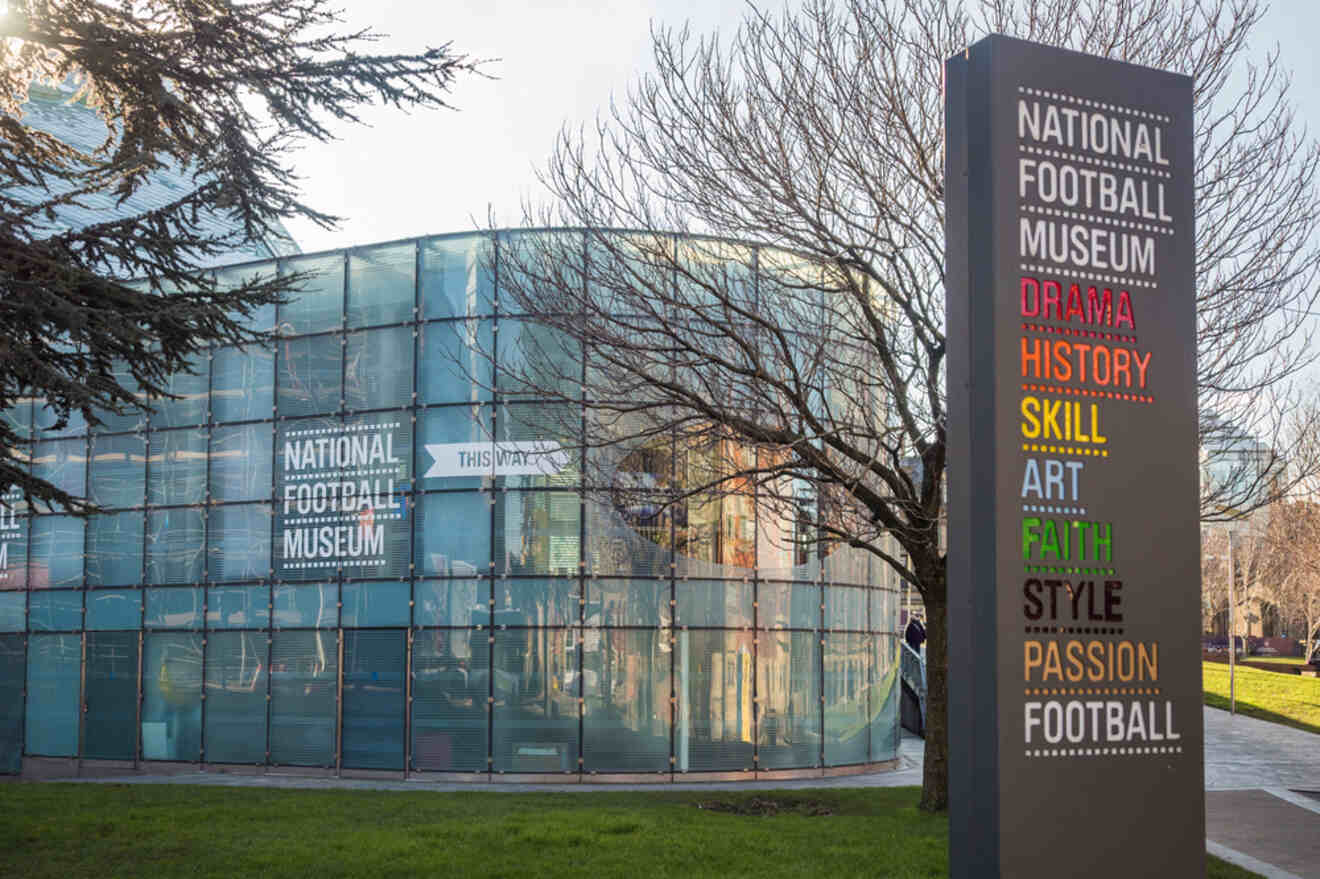 Visitors exploring the National Football Museum in Manchester, with colorful text describing 'Drama, History, Skill, Art, Faith, Style, Passion, Football' on the museum's exterior