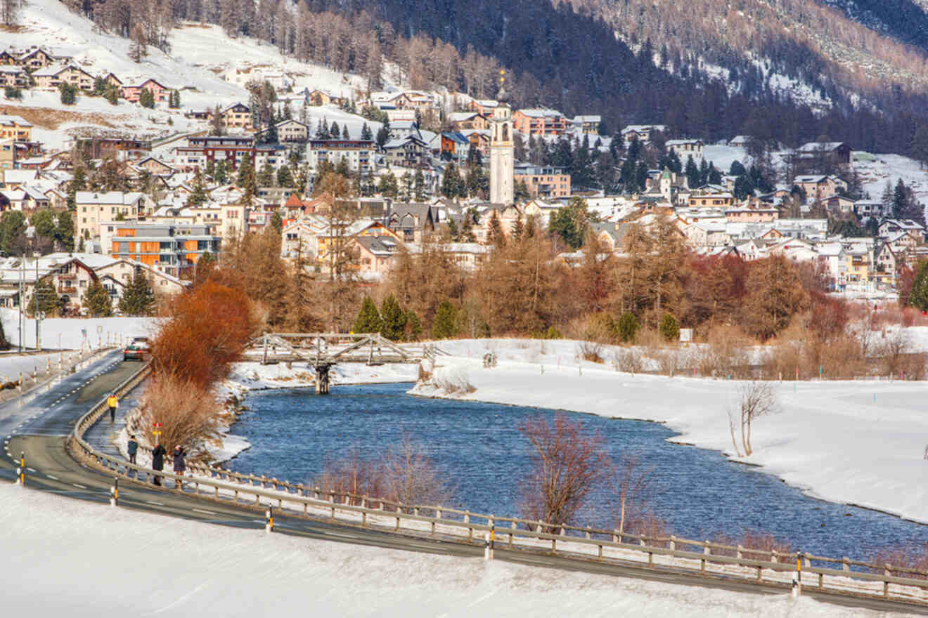 Winter view of Samedan near St. Moritz with a mix of modern and traditional buildings by a partly frozen river and snow-laden roads
