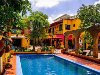 A vibrant pool area featuring warm yellow walls, terra cotta tiles, and a welcoming swimming pool