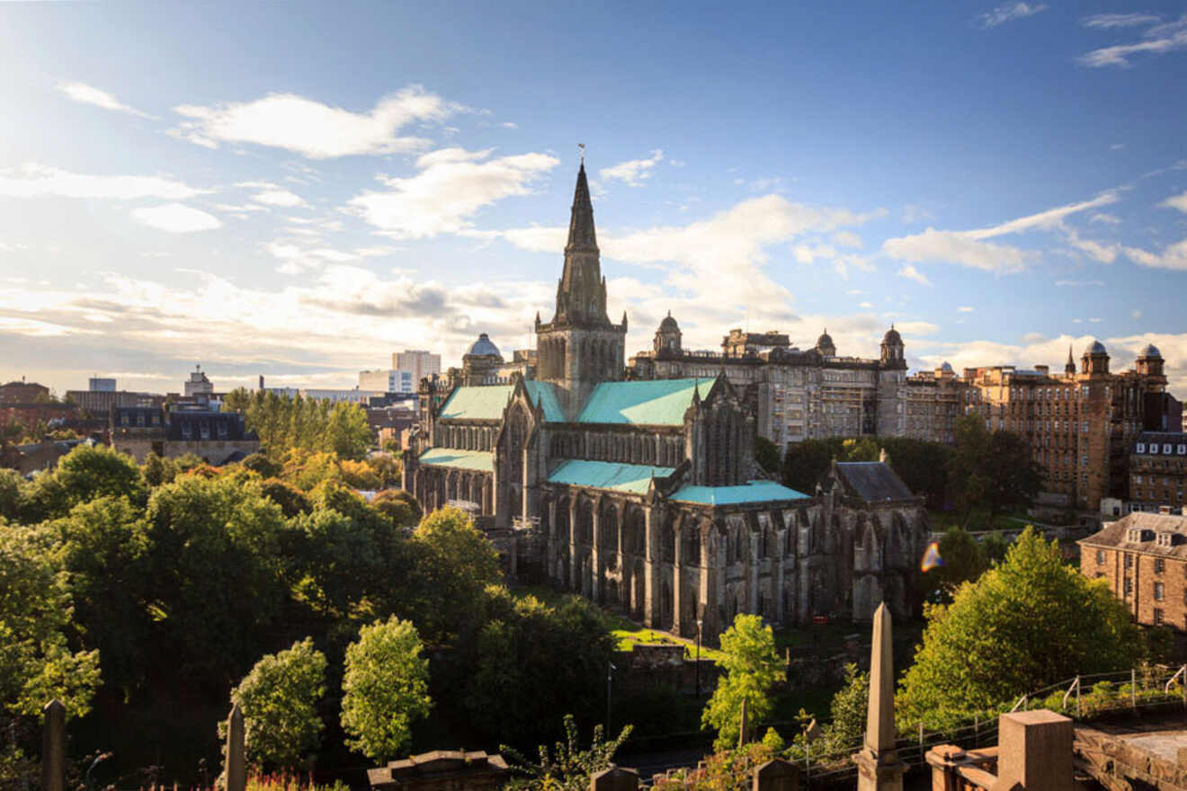 Sunlit view of Glasgow Cathedral and surrounding historic buildings amidst a lush urban landscape, embodying Glasgow East's cool and vibrant character