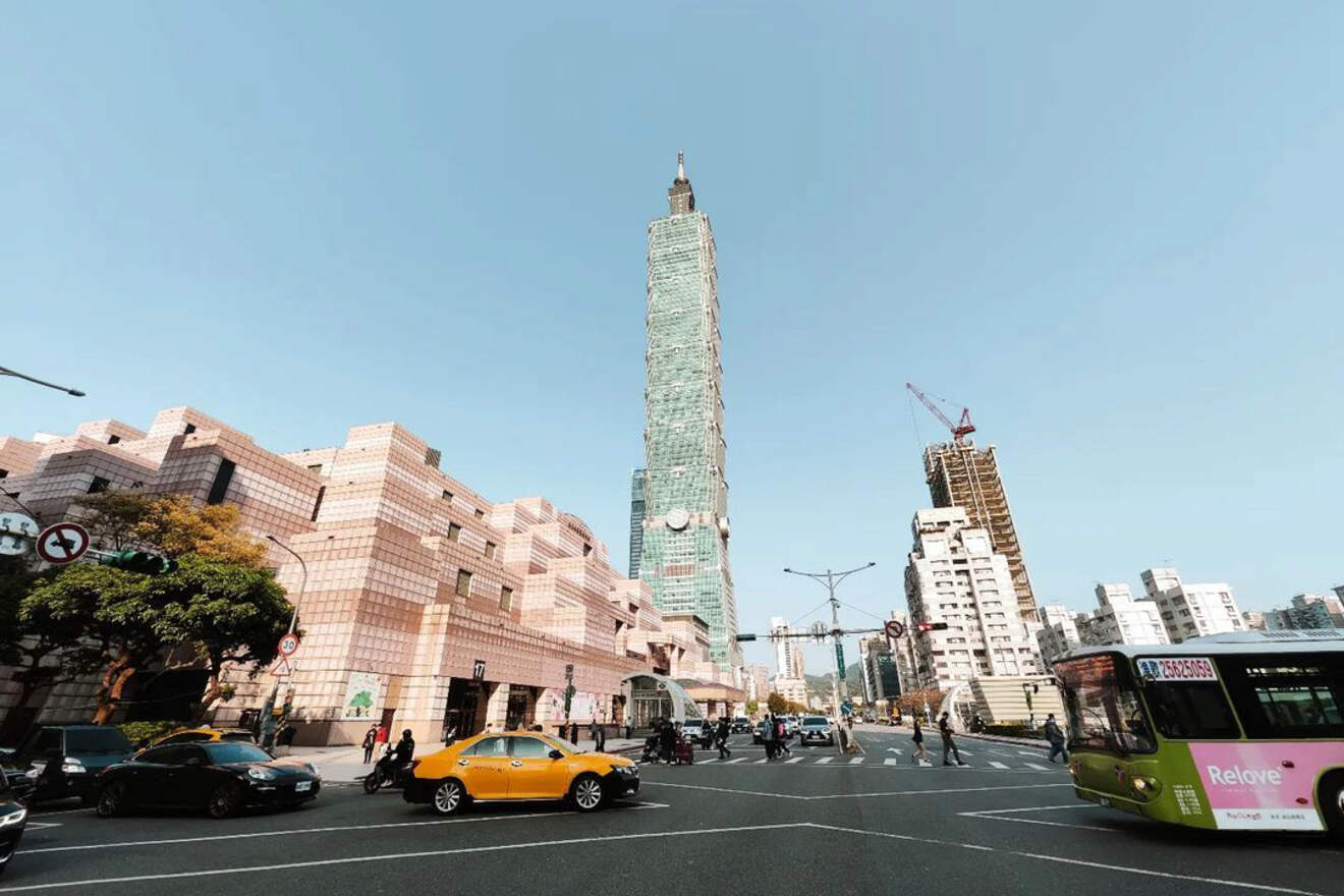 A wide street view in Taipei showing an eclectic mix of building architecture with the iconic Taipei 101 in the distance, indicative of the city's best apartments.