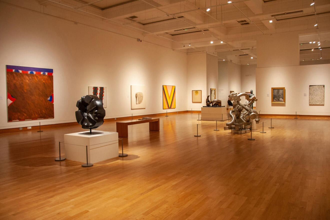 Spacious gallery inside the Ulster Museum in Belfast, displaying a variety of artworks and sculptures, with visitors quietly exploring the cultural offerings